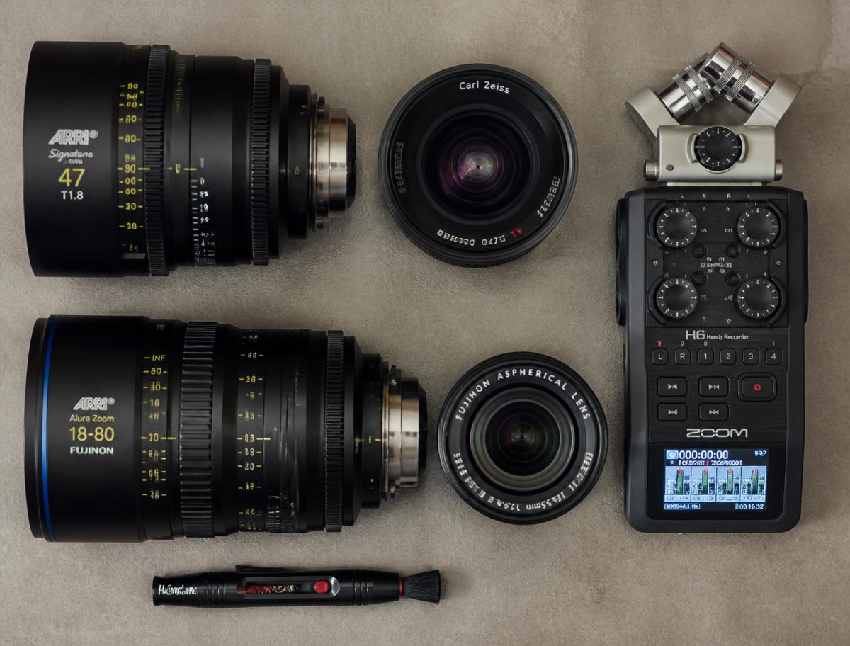 Cinema lenses and an audio recorder laid out on a warm grey surface
